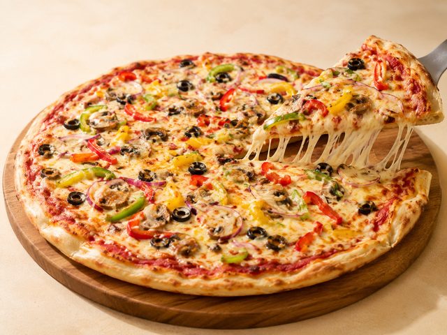 Fresh-baked pizza with a slice being lifted